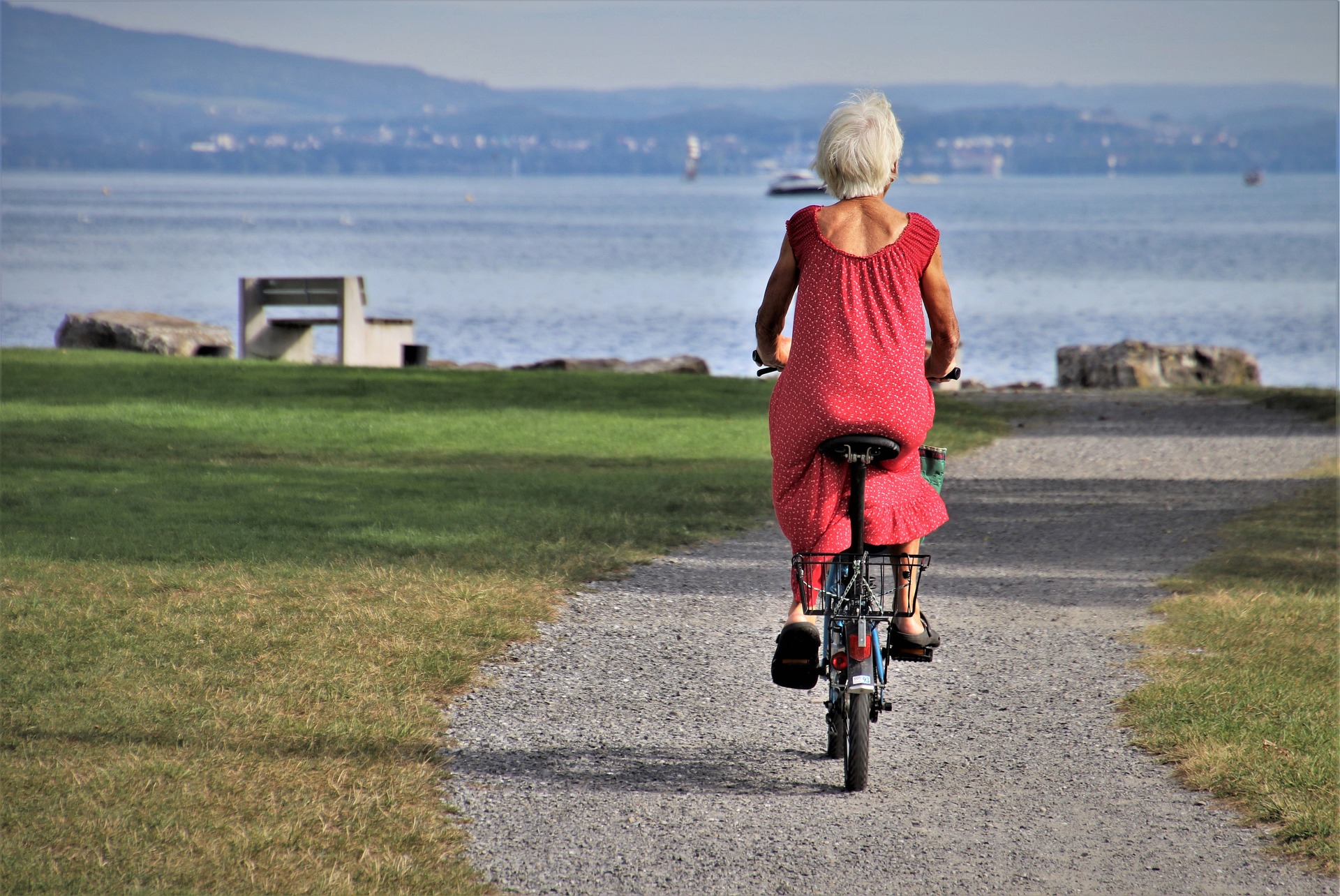 Äldre kvinna som cyklar i en park.