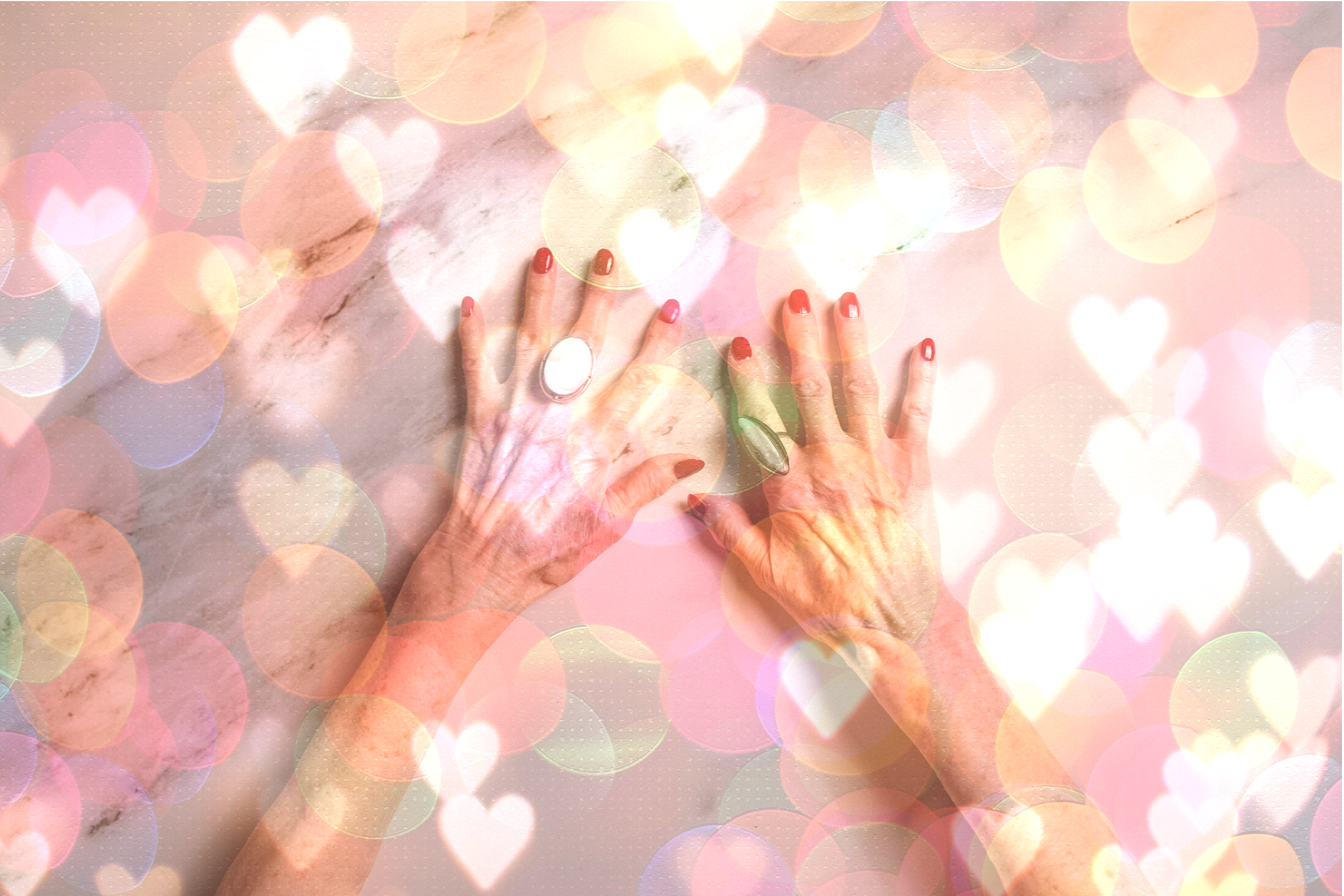 Händer som fångar ljuspunkter som är formade som hjärtan och cirklar