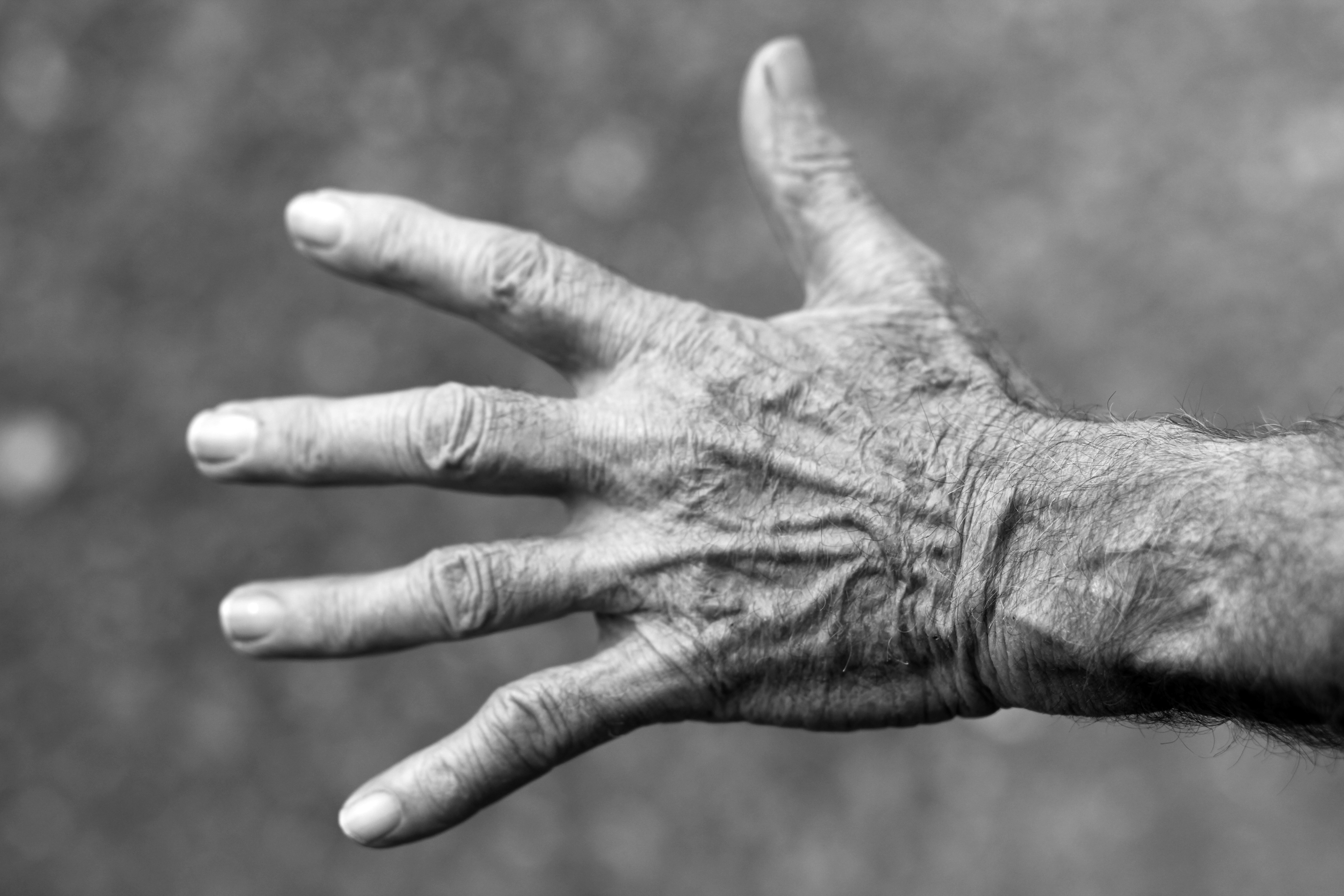 Svartvit bild på en äldre persons hand, med utsträckta fingrar